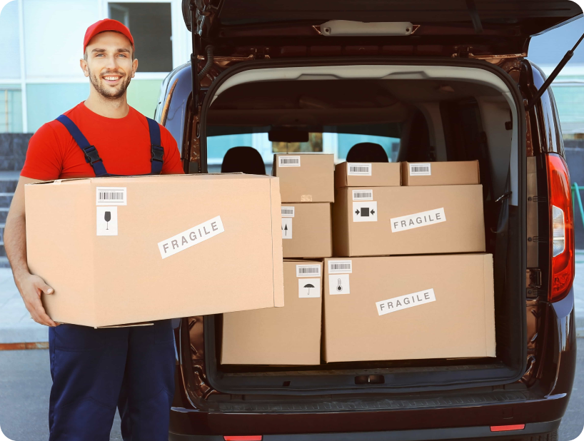 Un déménageur en hoodie rouge Déménagement WillGo déchargeant du matériel d’un camion près d’un immeuble résidentiel.