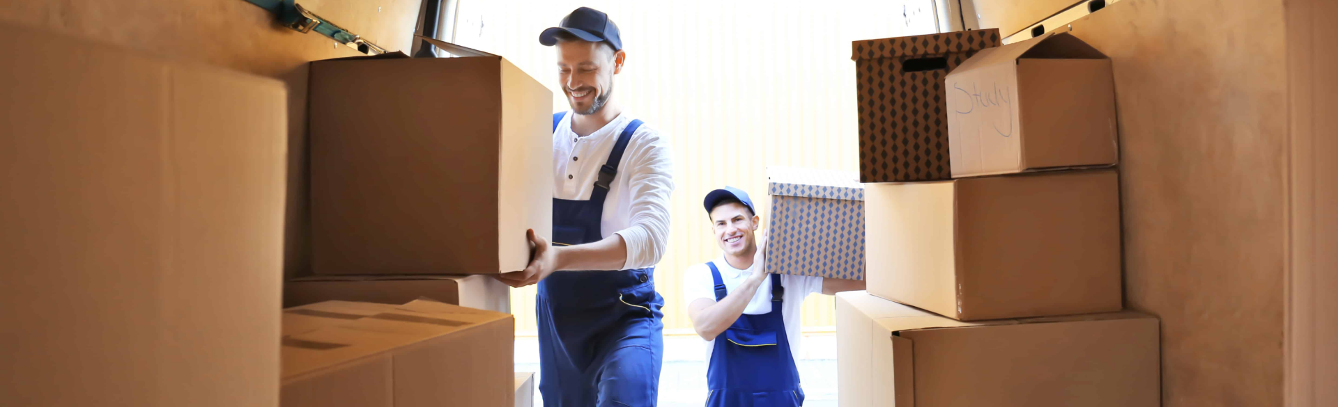 Nombreuses boîtes de déménagement en carton empilées devant des maisons résidentielles lors d'un déménagement.