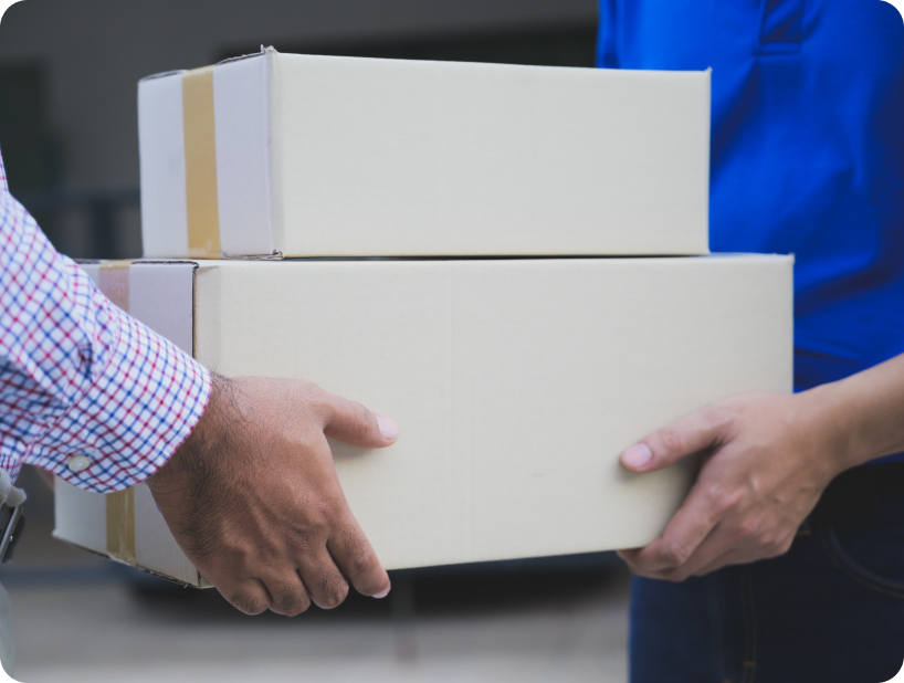 Deux personnes échangent deux boîtes en carton, illustrant un service de livraison ou de transfert offert par l’équipe de Déménagement WillGo.