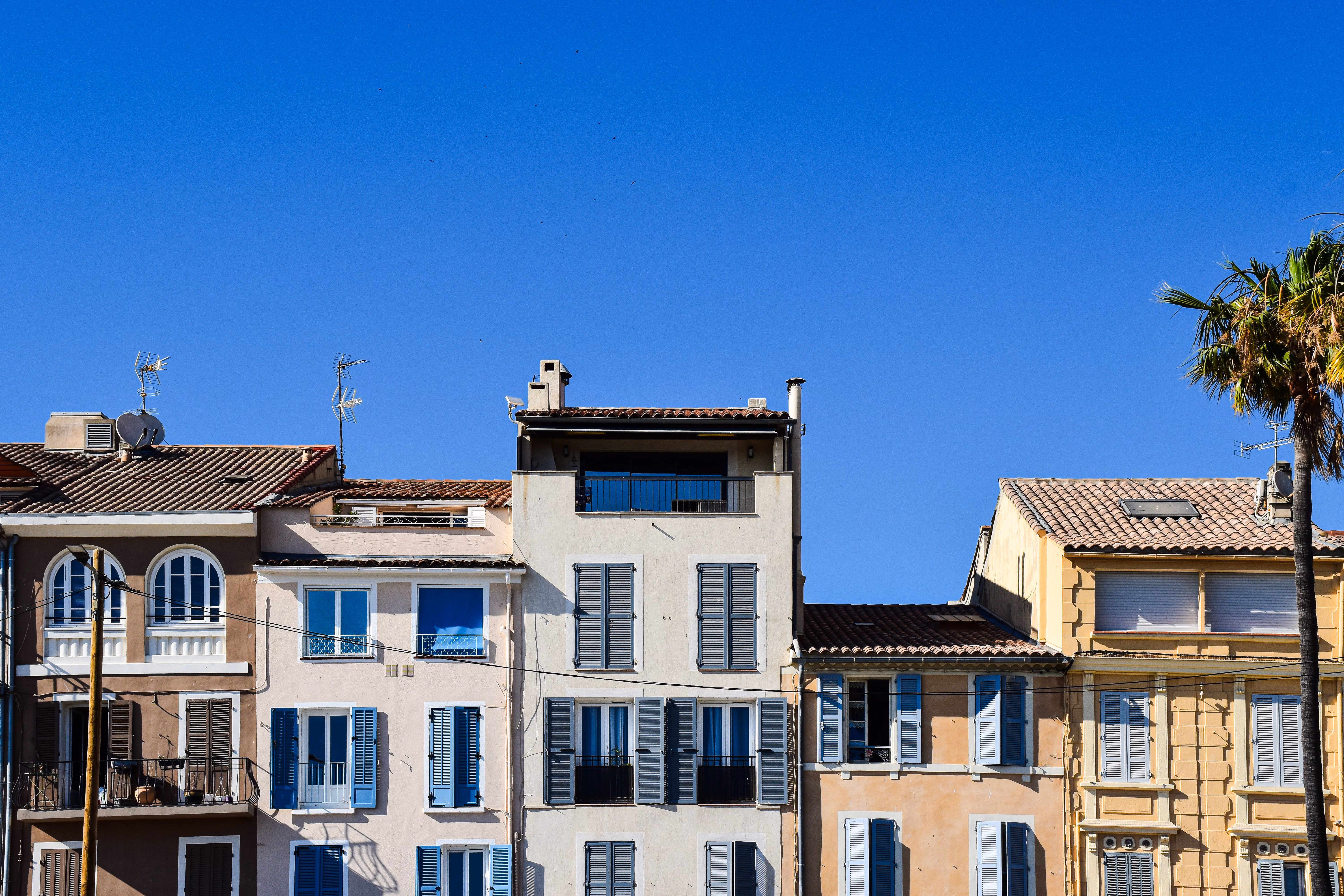 Immeubles résidentiels avec volets bleus et toits de tuiles sous un ciel bleu dégagé