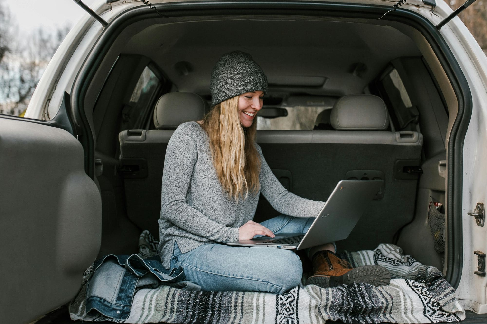 person sitting in the trunk of a car with laptop open
