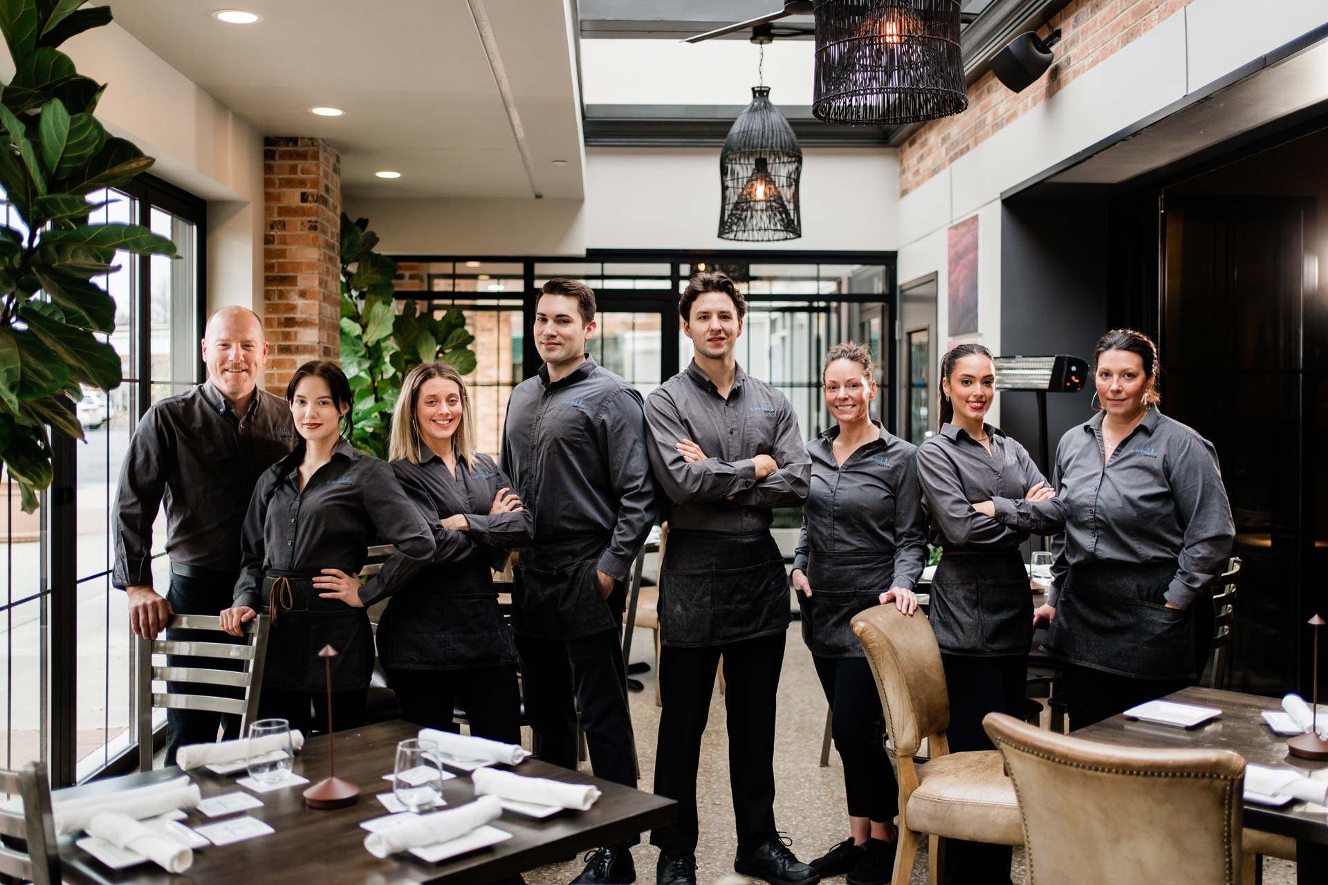 Restaurant staff members stand together inside a modern dining area.