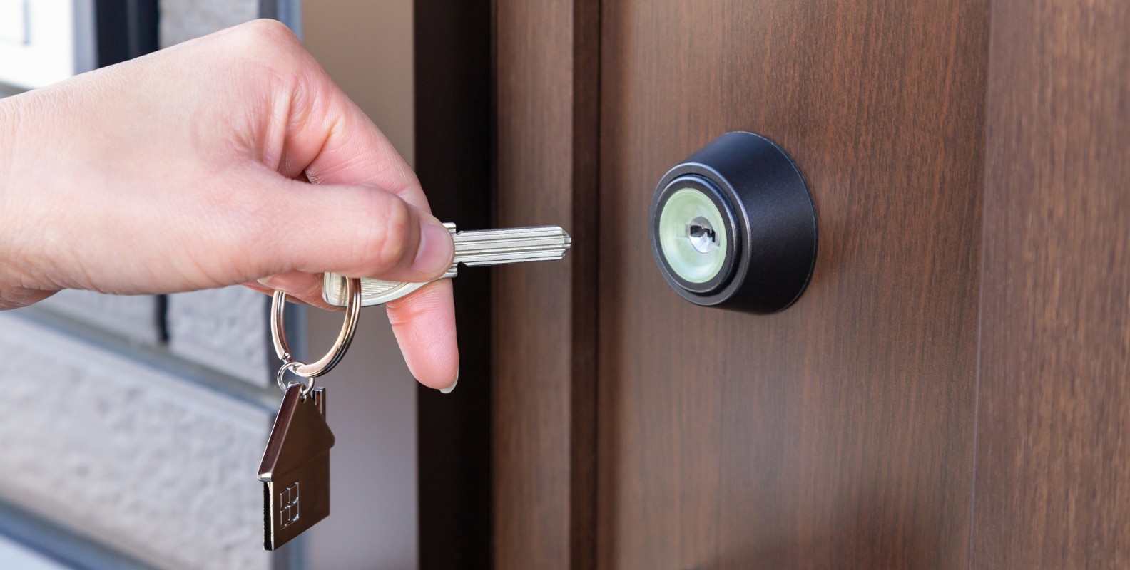 A hand holding a key, locking a front door