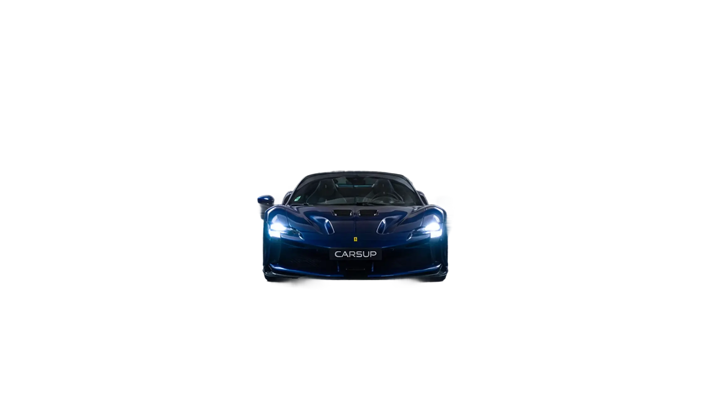 Front view of a blue Ferrari sports car with headlights on, centered against a plain light gray background, featuring a “CARSUP” plate on the front.