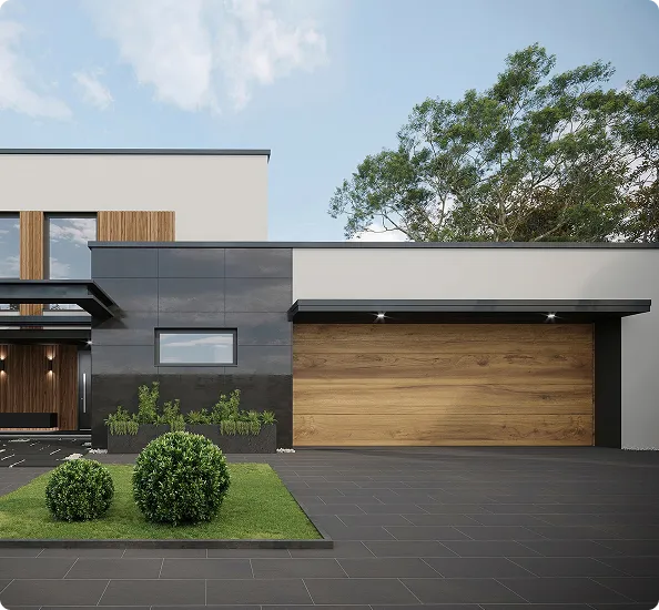 Façade d'une maison moderne avec garage au bois, revêtement noir brillant, arbustes verts et ciel clair.