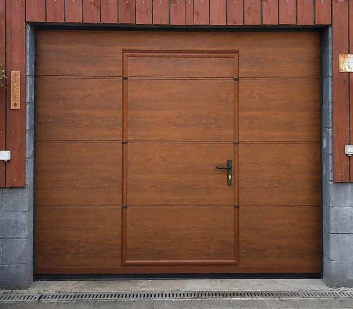 Porte de garage en bois avec une porte piétonne intégrée et poignée noire.