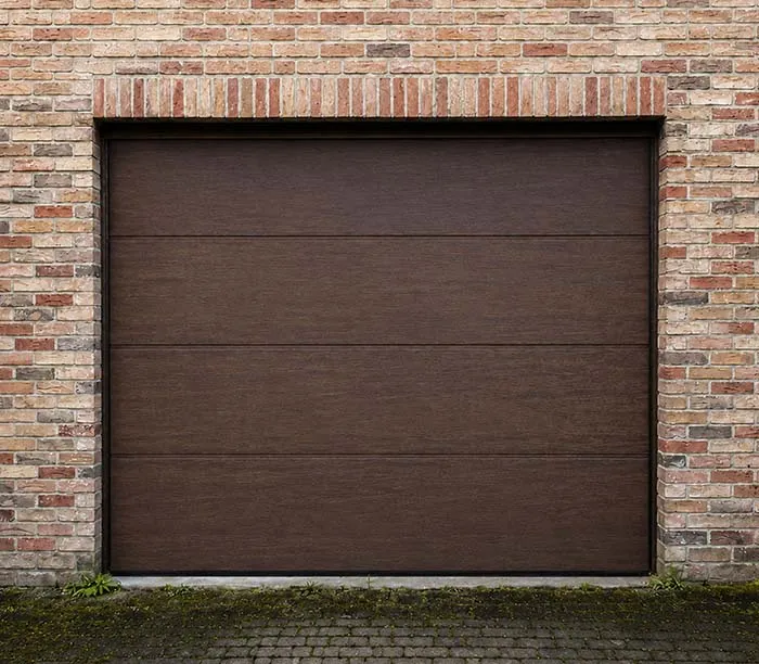 Porte de garage en bois foncé avec des panneaux horizontaux, entourée de murs en briques.