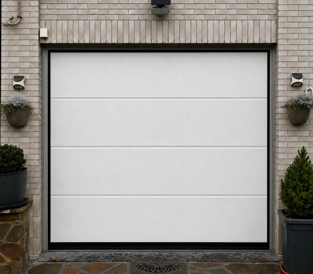 Porte de garage blanche moderne encadrée de briques claires avec deux pots de plantes de chaque côté.
