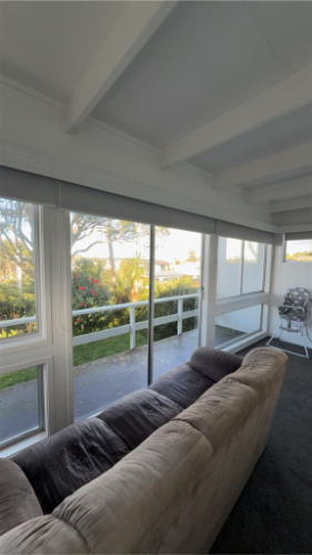 Sofa, windows with blinds, rocking chair.