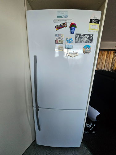 White refrigerator with various stickers and magnets on the front.