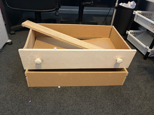 Wooden drawer with a white front and wooden dividers.