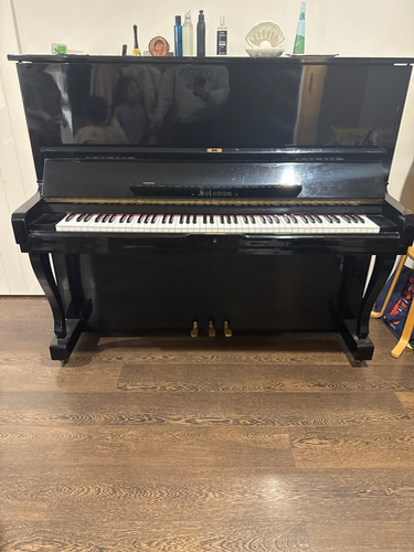 Upright piano with black finish and white keys.