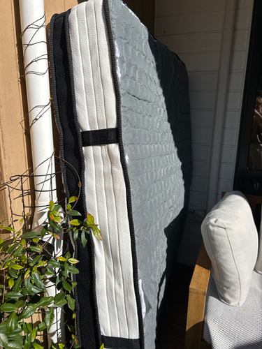 Folded mattress leaning against a wall.