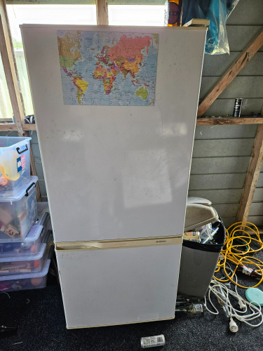 White refrigerator with a world map attached to the front.