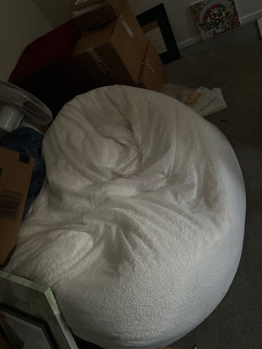 Large white bean bag chair surrounded by cardboard boxes.