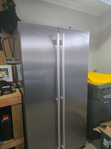 Stainless steel refrigerator with double doors, yellow lid bin, and green trash can.