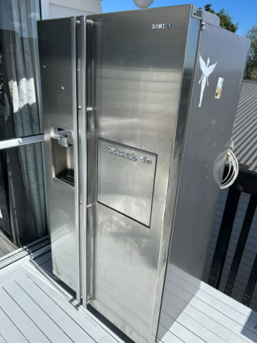 Stainless steel Samsung refrigerator with side-by-side doors and water dispenser.