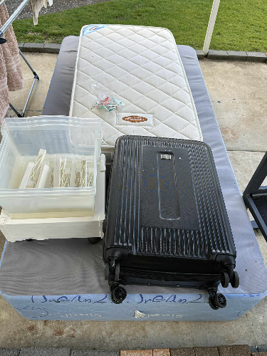 Black suitcase, clear storage container with items, white mattress.