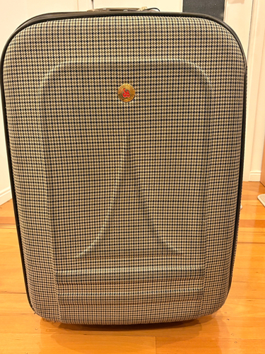 Black and white houndstooth patterned suitcase with a gold emblem.