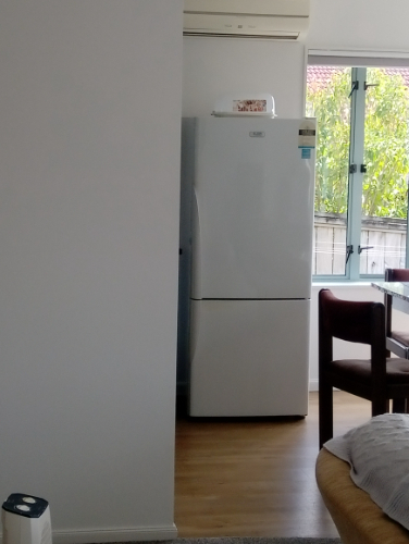 White refrigerator and wooden dining chairs.