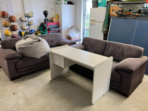 Two brown sofas, a white desk with drawers, and a gray bean bag chair.