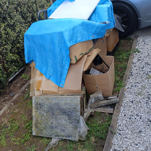 Cardboard boxes, blue tarpaulin, wooden planks, and a metal sheet.