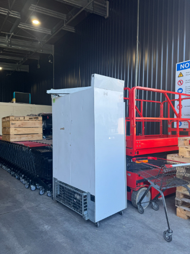 White refrigerator, red lift, shopping carts, wooden pallets.