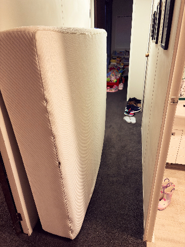 White mattress leaning against a wall in a hallway.