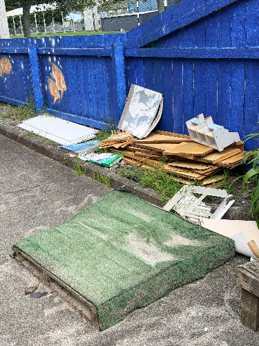 Green mat, cardboard boxes, stacked wooden boards, sheets of paper.