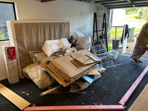 Mattress, cardboard boxes, plastic packaging, metal shelving unit, and wooden boards.