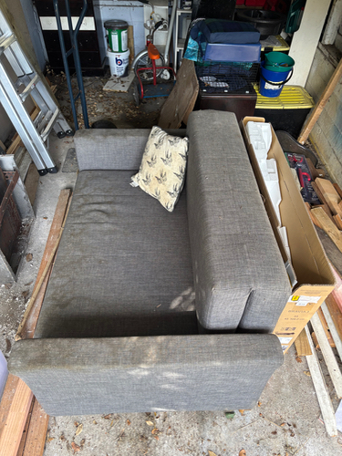 Gray sofa with a patterned cushion and cardboard box.