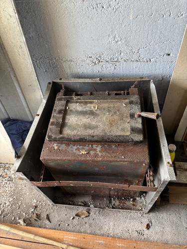 Old, rusty metal furnace with a solid lid.