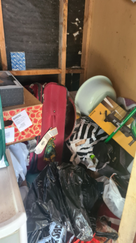 Red suitcase, green chair, black garbage bag, white bowl, patterned fabric, cardboard boxes.