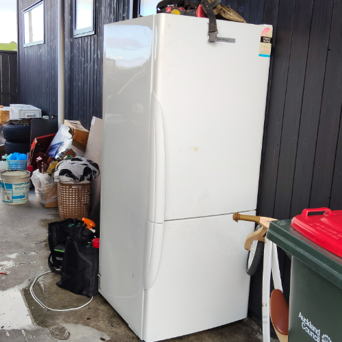White refrigerator, trash can with red lid, bags, assorted items in a basket.