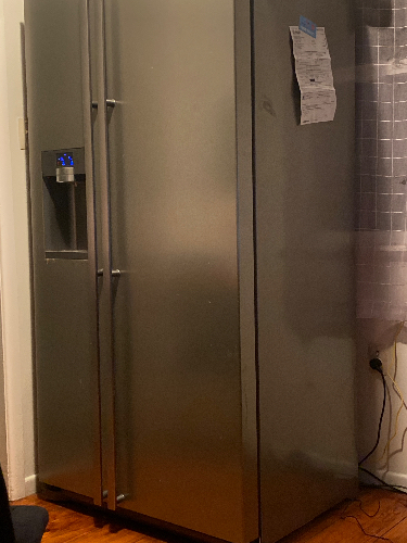 Stainless steel refrigerator with water dispenser and notes attached.