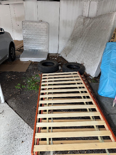 Wooden bed frame, two mattresses, two tires, blue tarp.