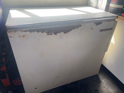 Chest freezer with visible rust and wear.