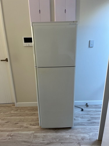 White refrigerator with a top freezer and a lower refrigerator compartment.