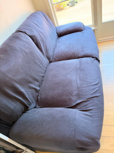 Dark brown fabric couch with one armrest.