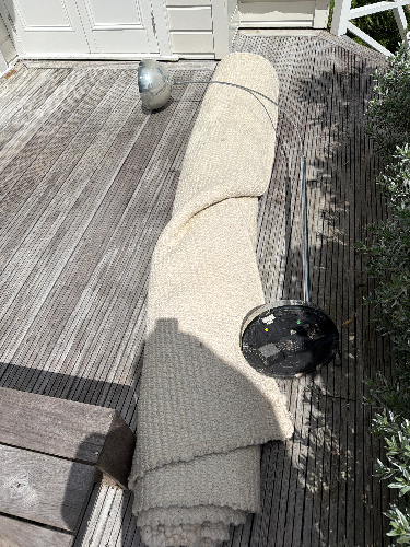 Rolled beige rug, black round plate, metallic decorative object.