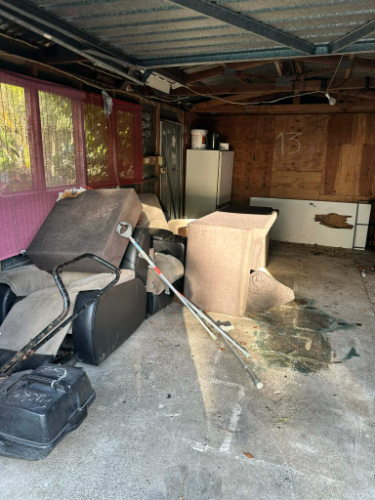 Reclining chair, sofa, table, fridge, broom, clutter.