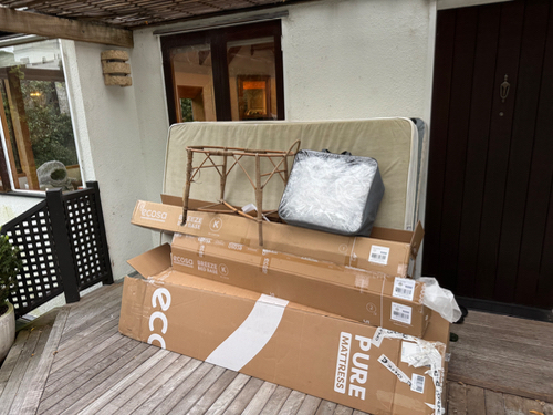 Mattress, cardboard boxes, folding table frame, plastic-wrapped item.