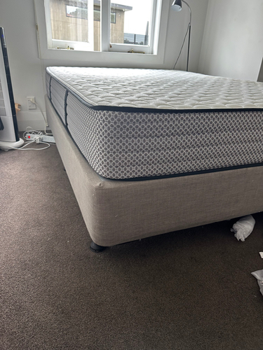 Queen-sized mattress on a beige bed frame.