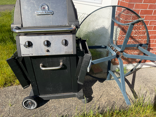 Black gas grill and glass-topped outdoor table.