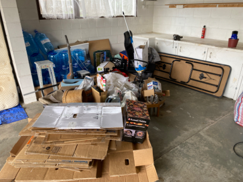 Cardboard boxes, plastic water bottles, a vacuum cleaner, a folding table, a toolbox, and assorted household items.