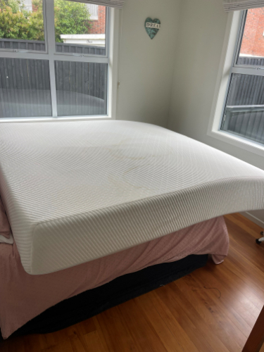 White mattress on a pink bedspread.