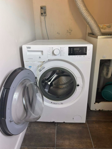 Washing machine with door open, silver drum visible.