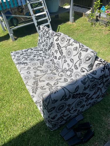 Sofa with floral pattern and several black items on the ground.