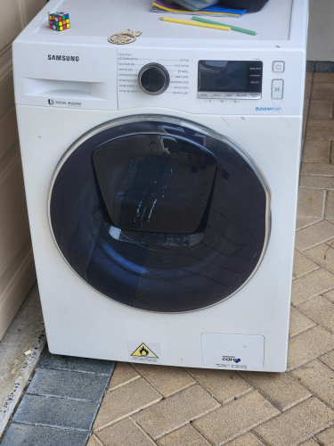 Samsung washing machine with a dark front door and control panel.