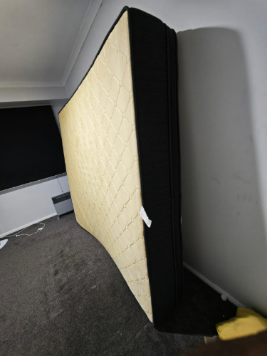 Black and cream mattress leaning against a wall.